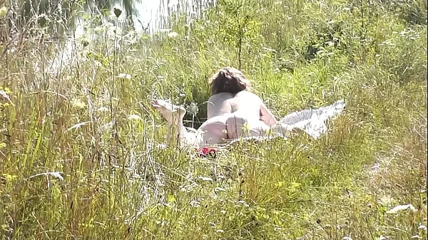 A casual passerby young guy saw a naked Milf sunbathing on river bank. Peeping. Spy camera. Naked in public. Nude beach. Wild beach